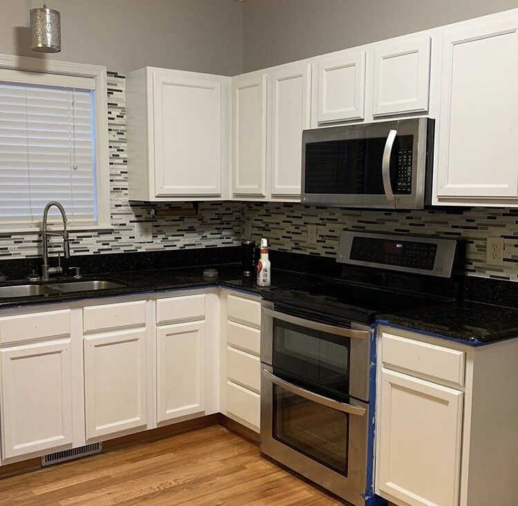 Kitchen with white cabinets, black countertops and stainless appliances